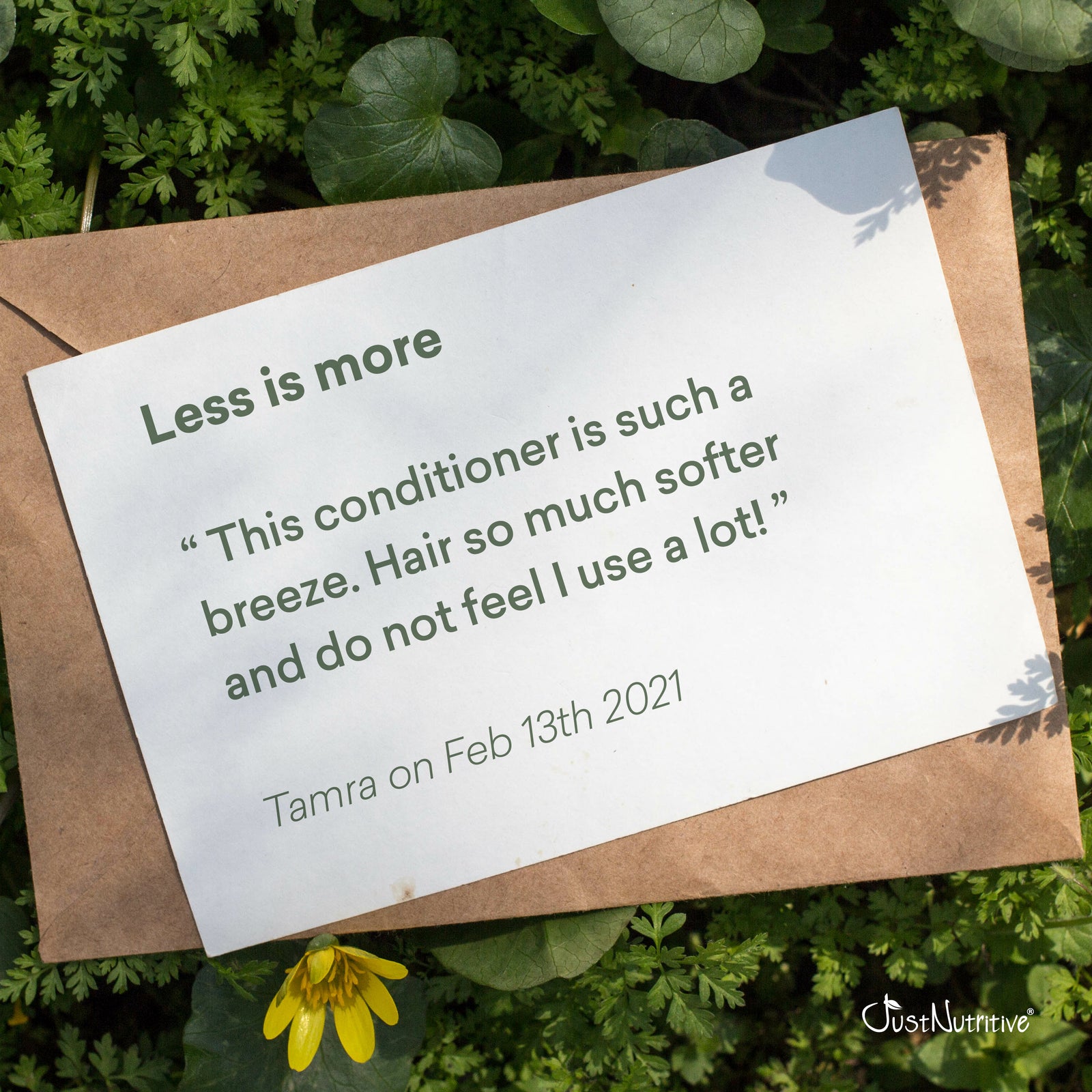Note on a brown envelope with text about hair conditioner, placed on green foliage.